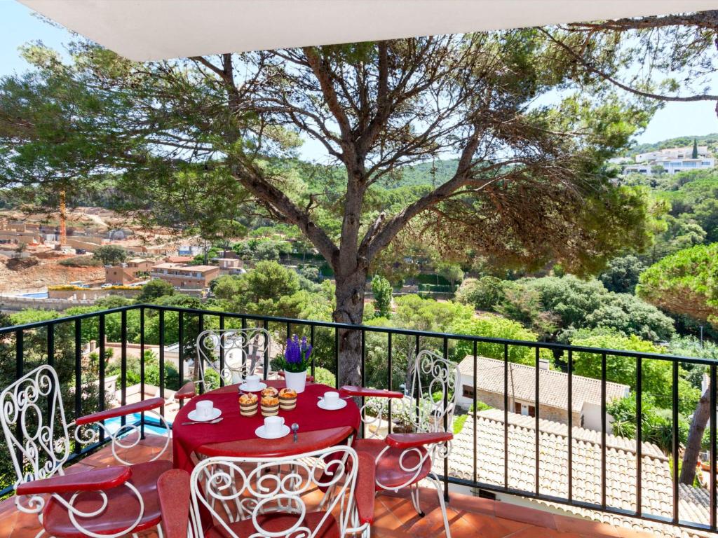 une table et des chaises rouges sur un balcon avec un arbre dans l'établissement Apartment S'Olivera-2 by Interhome, à Begur