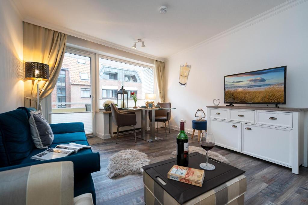 ein Wohnzimmer mit einem blauen Sofa und einem TV in der Unterkunft Meeresrauschen in Westerland