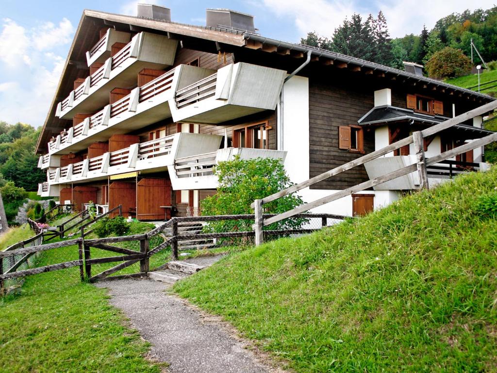 un bâtiment sur une colline avec une clôture devant lui dans l'établissement Apartment Cassiopée 26 by Interhome, à Les Rasses