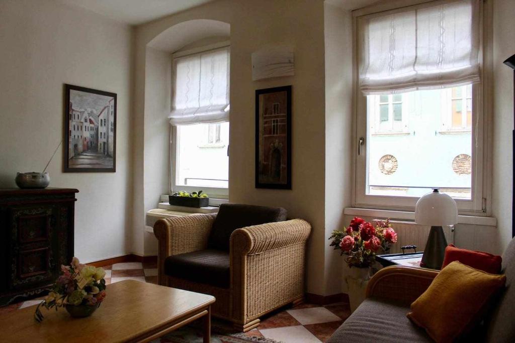 sala de estar con silla, mesa y 2 ventanas en Appartamento La Contrada, en Trento