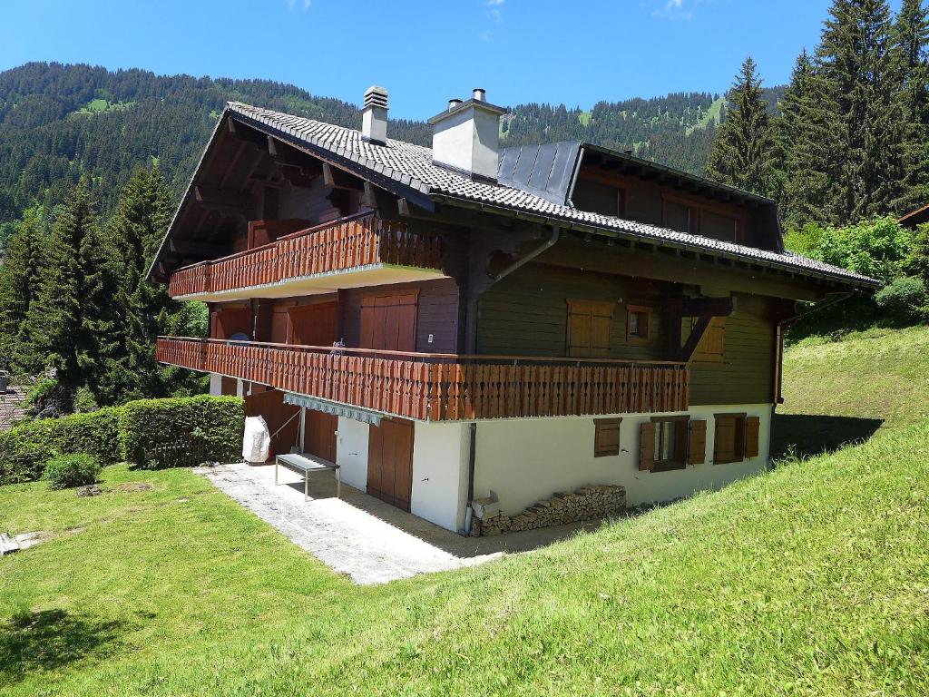 a large wooden house on a hill in a field at Apartment Le Bouquetin 5 by Interhome in Villars-sur-Ollon