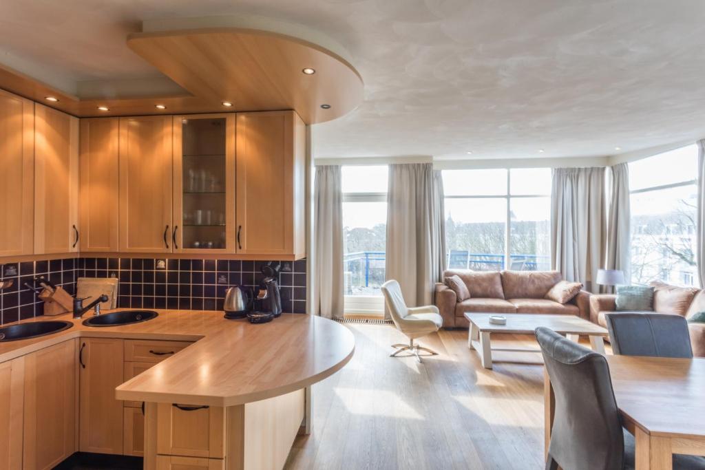een keuken en een woonkamer met een bank en een tafel bij Hello Zeeland - Appartement Loverendale 31 in Domburg