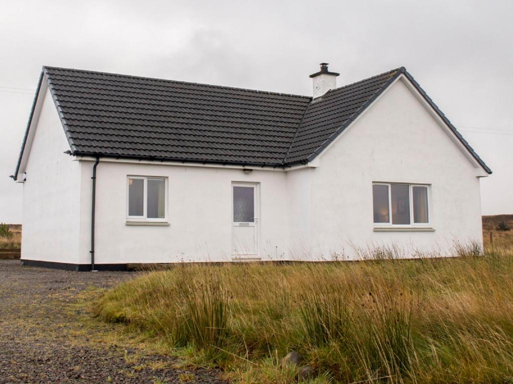 une maison blanche avec un toit noir sur un champ dans l'établissement Holiday Home An Caladh by Interhome, à Harlosh