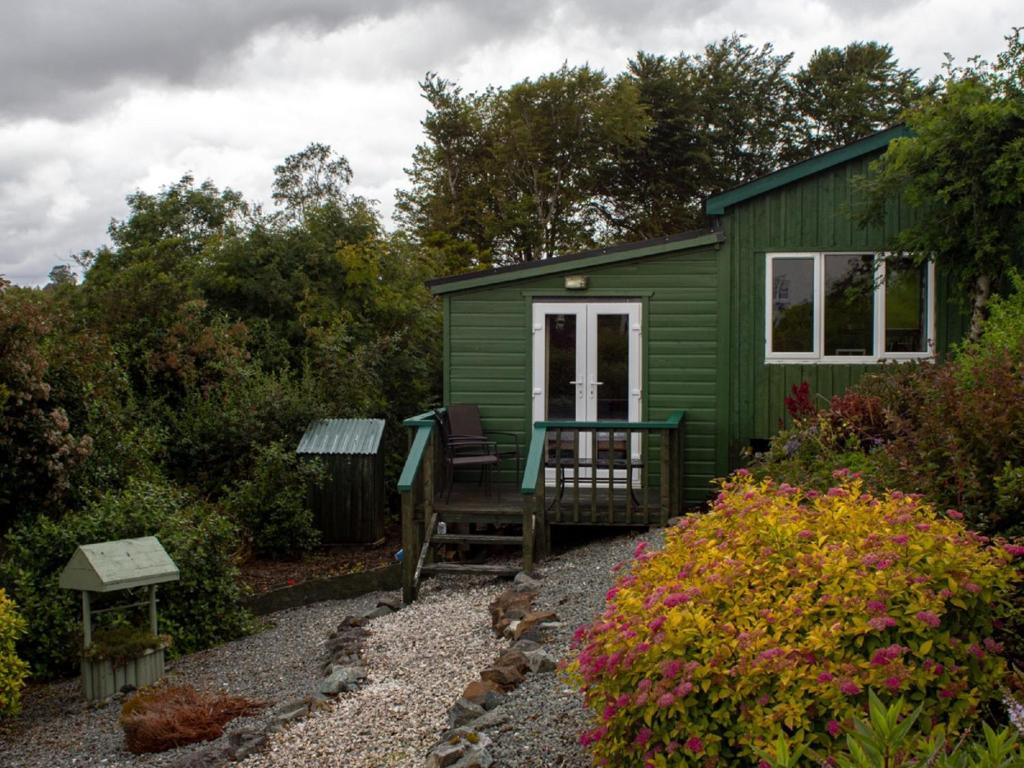 a green shed with a picnic table in front of it at Chalet Skye Garden Accommodation by Interhome in Portree