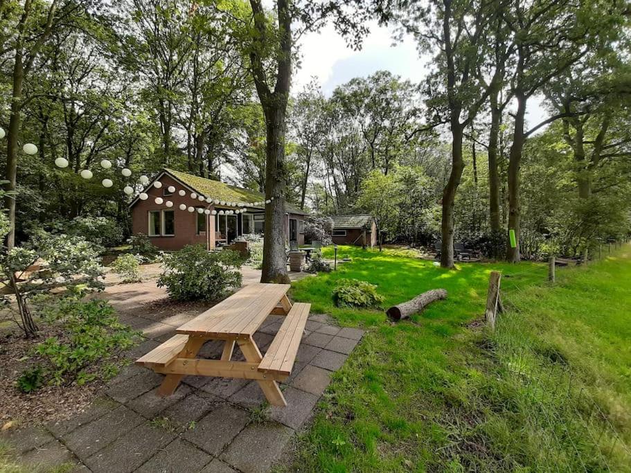 a wooden picnic table in a yard next to a house at Boshuisje Doldersum: omheinde tuin en uniek uitzicht in Doldersum