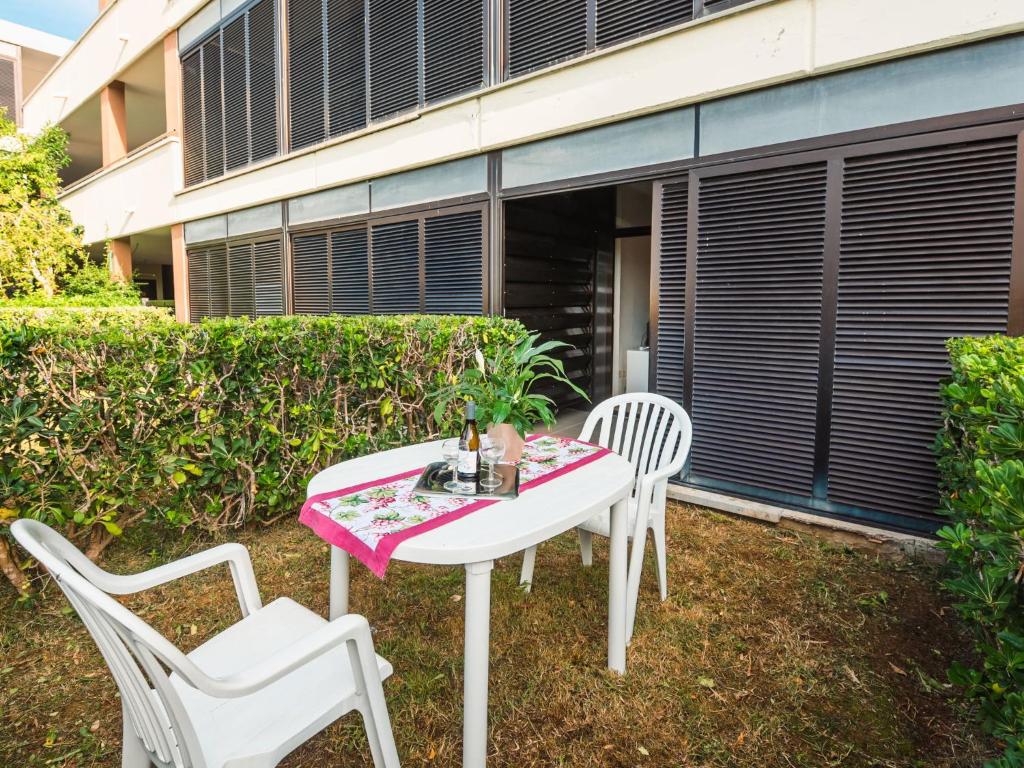 Biały stół i dwa krzesła na trawie w obiekcie Apartment Bilo Standard Garden-4 by Interhome w mieście Marina di Bibbona