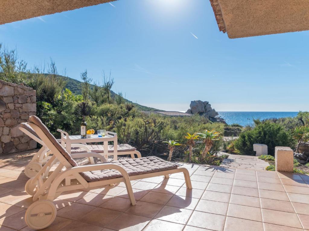 un patio con mesa, sillas y el océano en Holiday Home Morellino by Interhome, en Aglientu