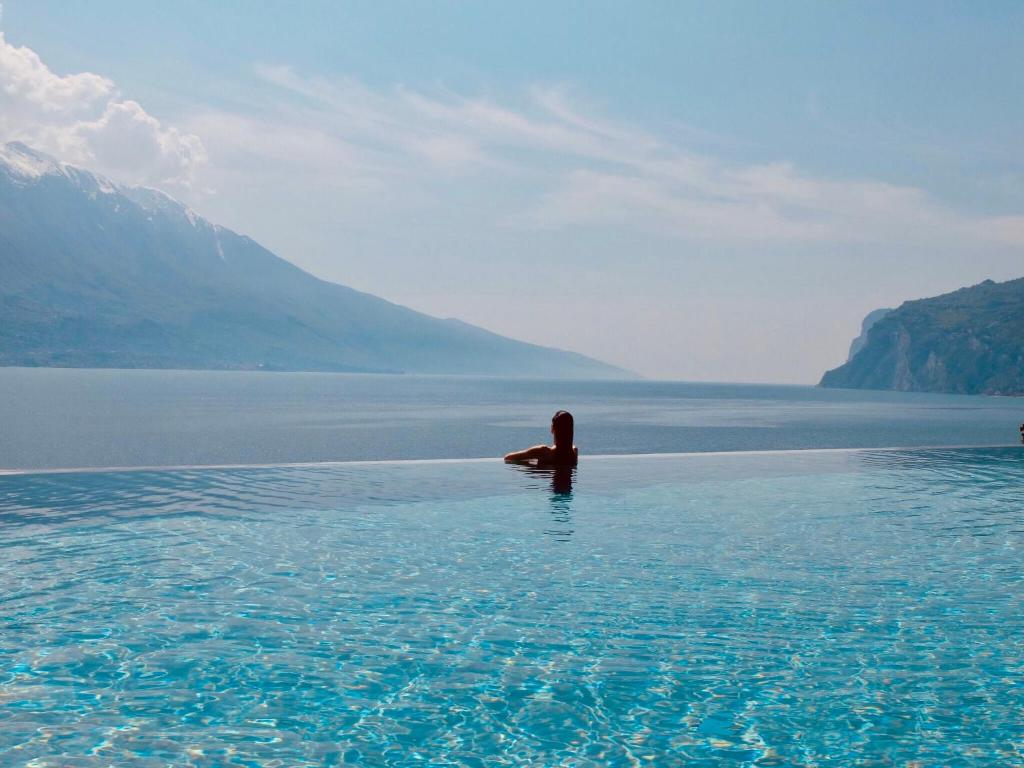 a person swimming in a body of water at EALA My Lakeside Dream - Adults Friendly in Limone sul Garda