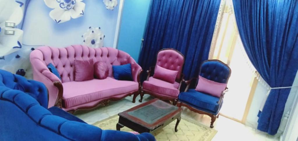 un soggiorno con sedie rosa e blu e un divano di الهرم a Il Cairo