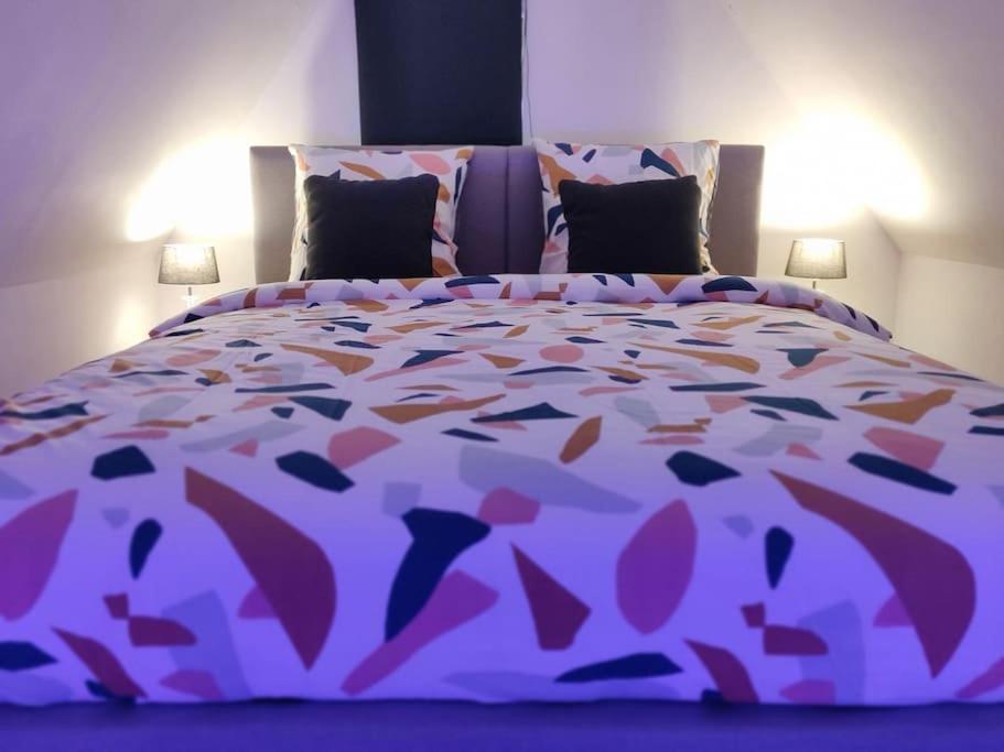 un grande letto con piumone e cuscini viola di Très Bel appart charmant 85m2 parking gratuit a Molsheim