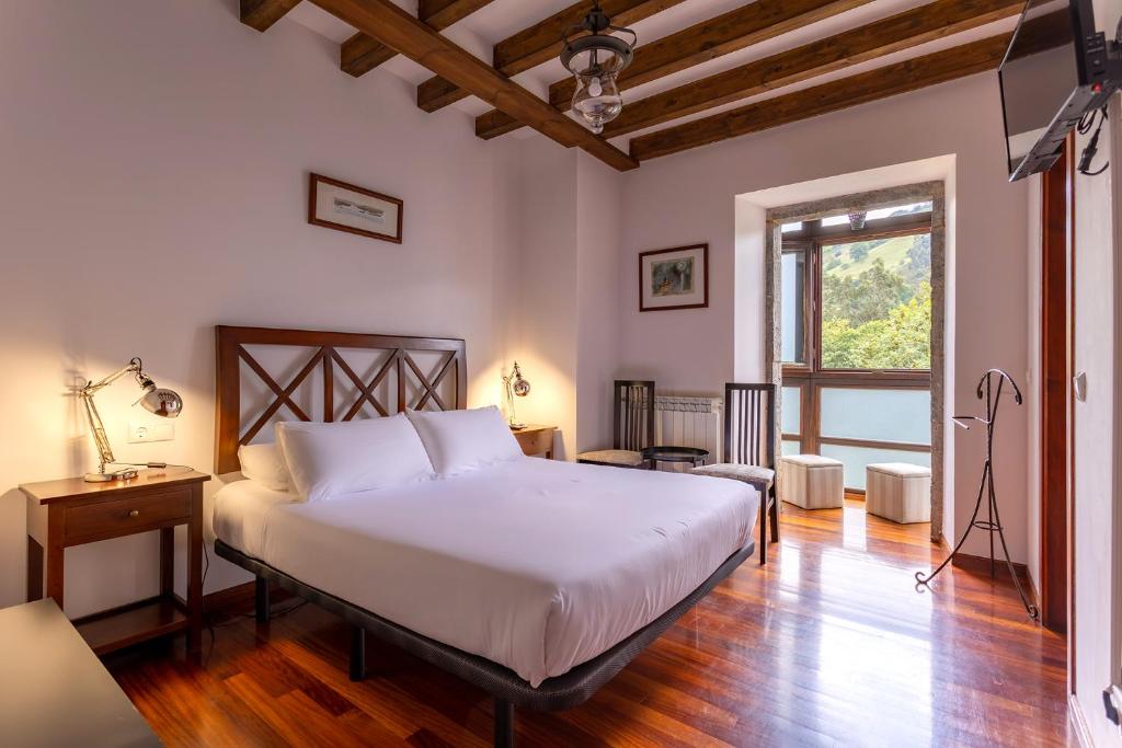 Un dormitorio con una gran cama blanca y una ventana en Posada 3 Valles, en Liérganes