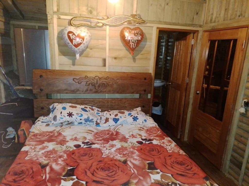 1 dormitorio con 1 cama con rosas y corazones en la pared en la casita del arbol guaduas cundi. en Guaduas