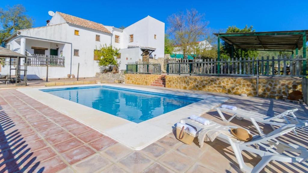 una piscina con 2 sillas y una casa en Cuesta Blanca Montilla by Ruralidays, en Montilla