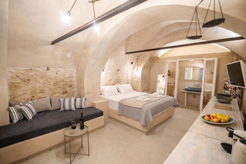 a bedroom with a bed and a couch and a table at Oia's Cellars in Oia