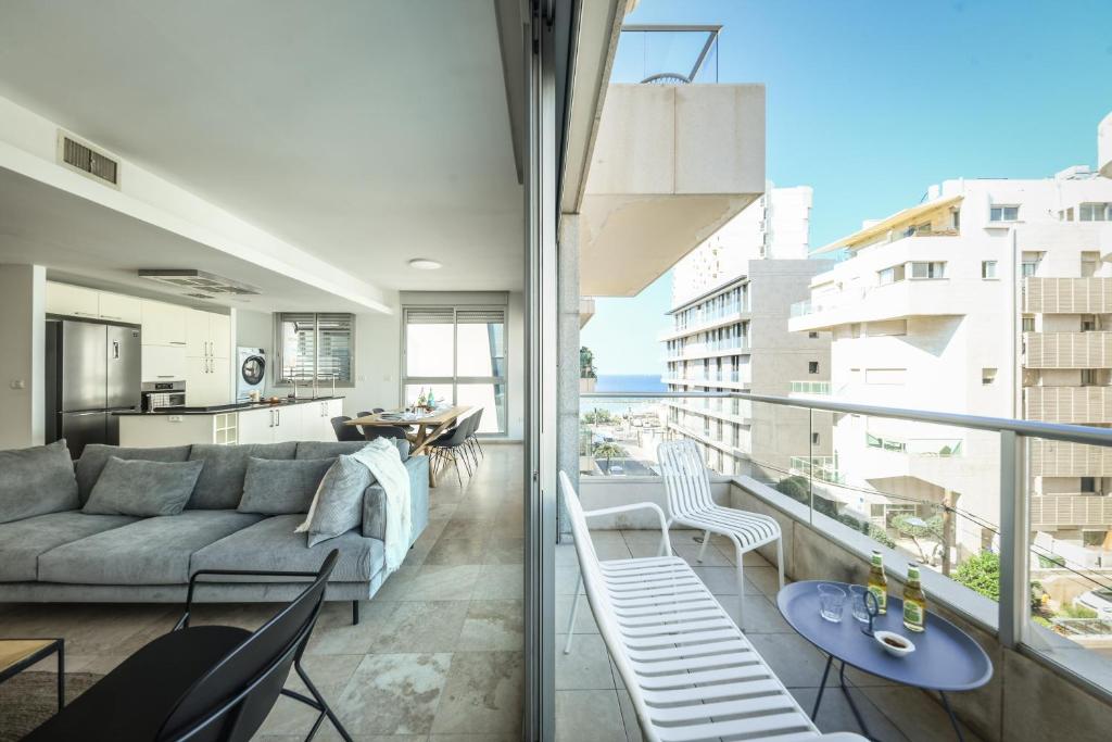 sala de estar con sofá, mesa y sillas en Chic Apartment w Balcony, Mamad & Parking 3-min from Beach by Sea N' Rent en Tel Aviv