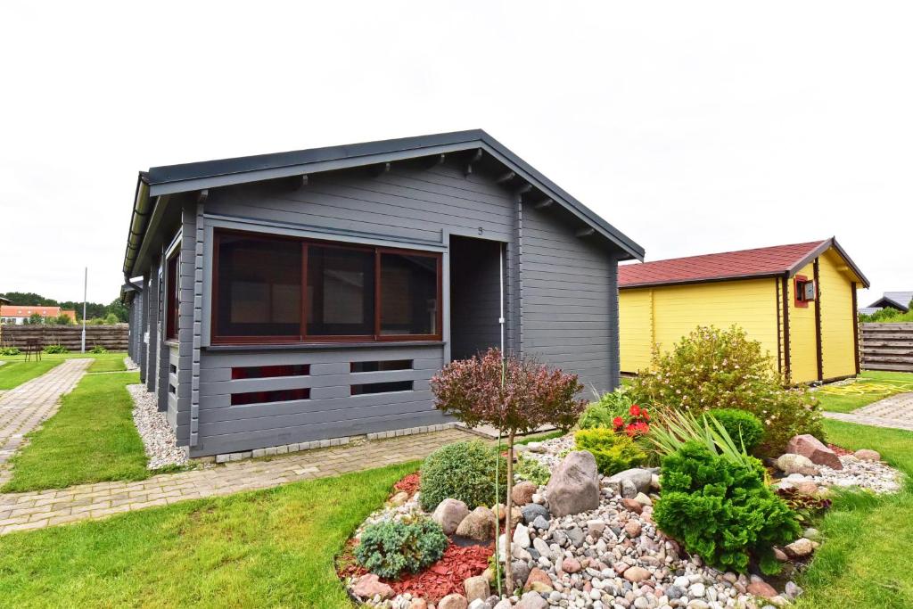 a small grey house with a garden in front of it at Nameliai Gulbės takas in Šventoji