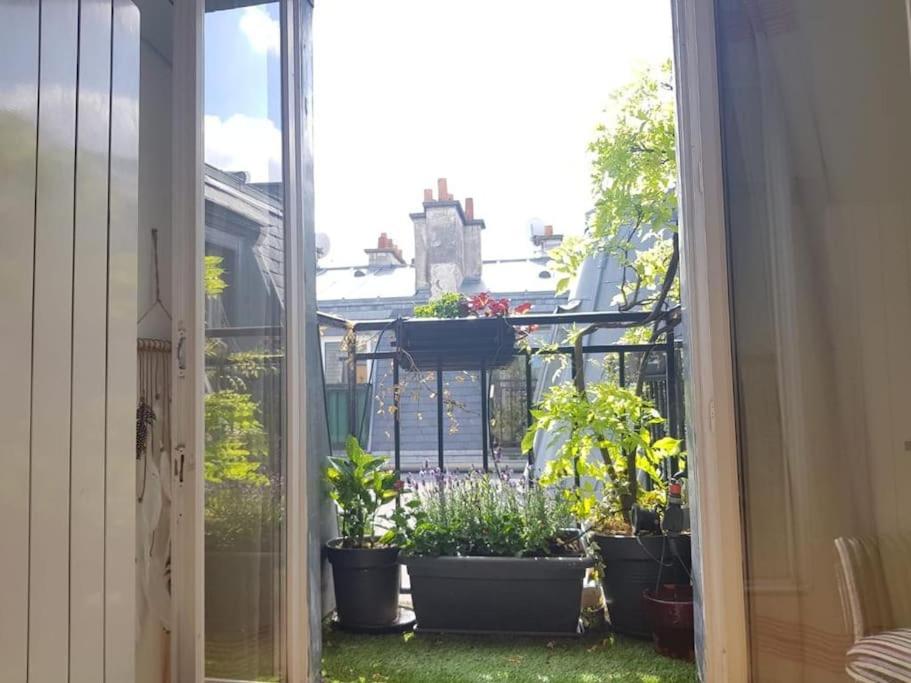 an open window with potted plants on a balcony at Modern Design One Bedroom Apartment in Paris