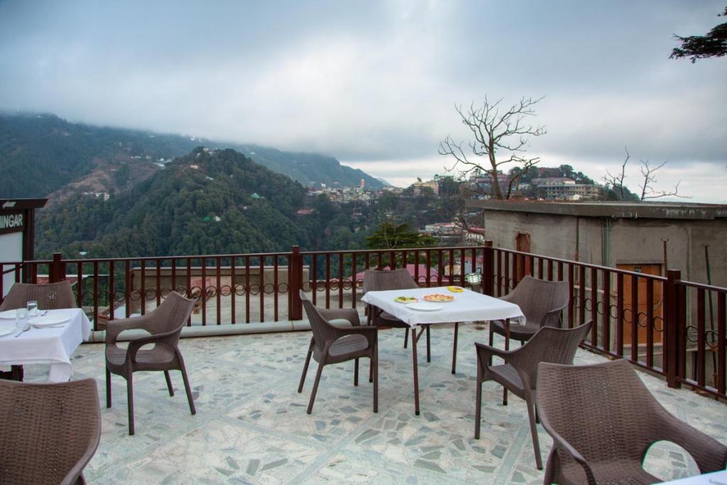 a patio with tables and chairs on a balcony at Hotel Sunny Cot Mussoorie Mallroad in Mussoorie