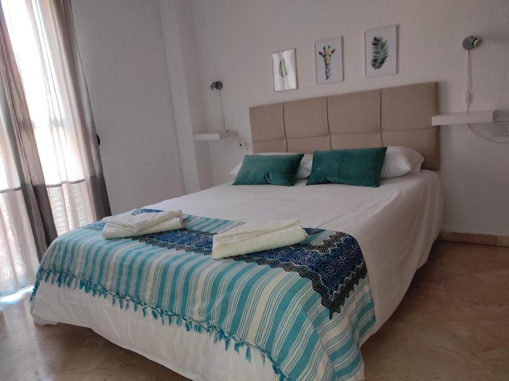 1 dormitorio con 1 cama grande con almohadas verdes y azules en Vive Huelva ARAGON 4 HABITACIONES WIFI 300MB en Huelva