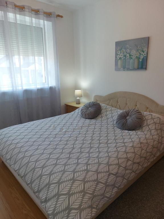 a bed with two pillows on it in a bedroom at Apartman Dane in Kikinda