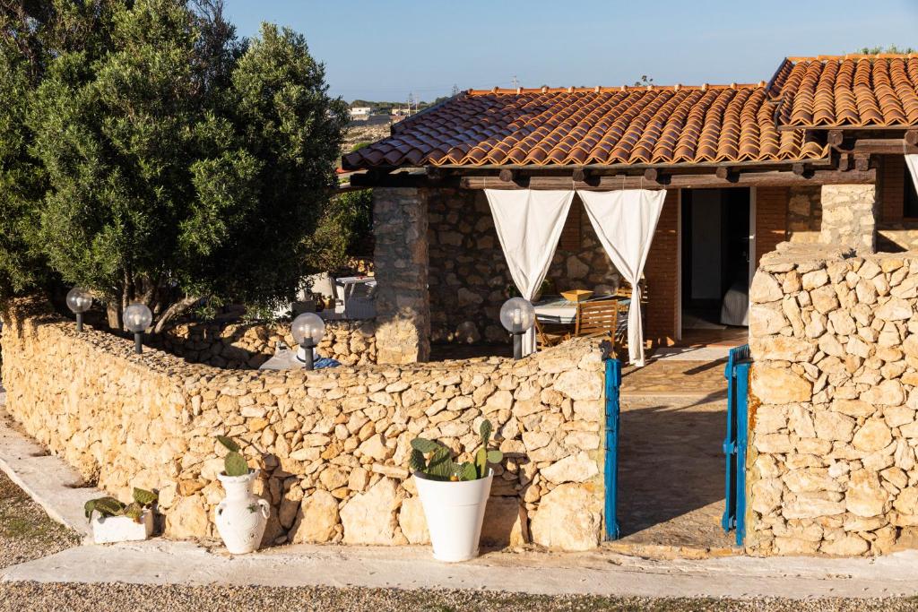 uma parede de pedra com vasos de plantas em frente a uma casa em Dammusi Ziunì em Lampedusa
