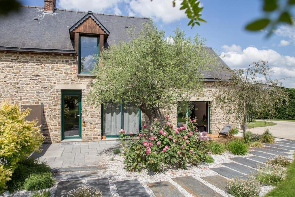 una casa de ladrillo con un árbol delante de ella en Gîte à la campagne, en Coësmes