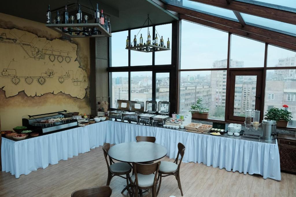 een tafel en stoelen in een kamer met ramen bij Konyak Hotel in Jerevan