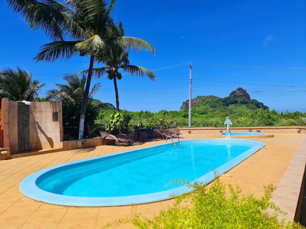 a swimming pool in a resort with a palm tree at Pousada Sueste in Fernando de Noronha