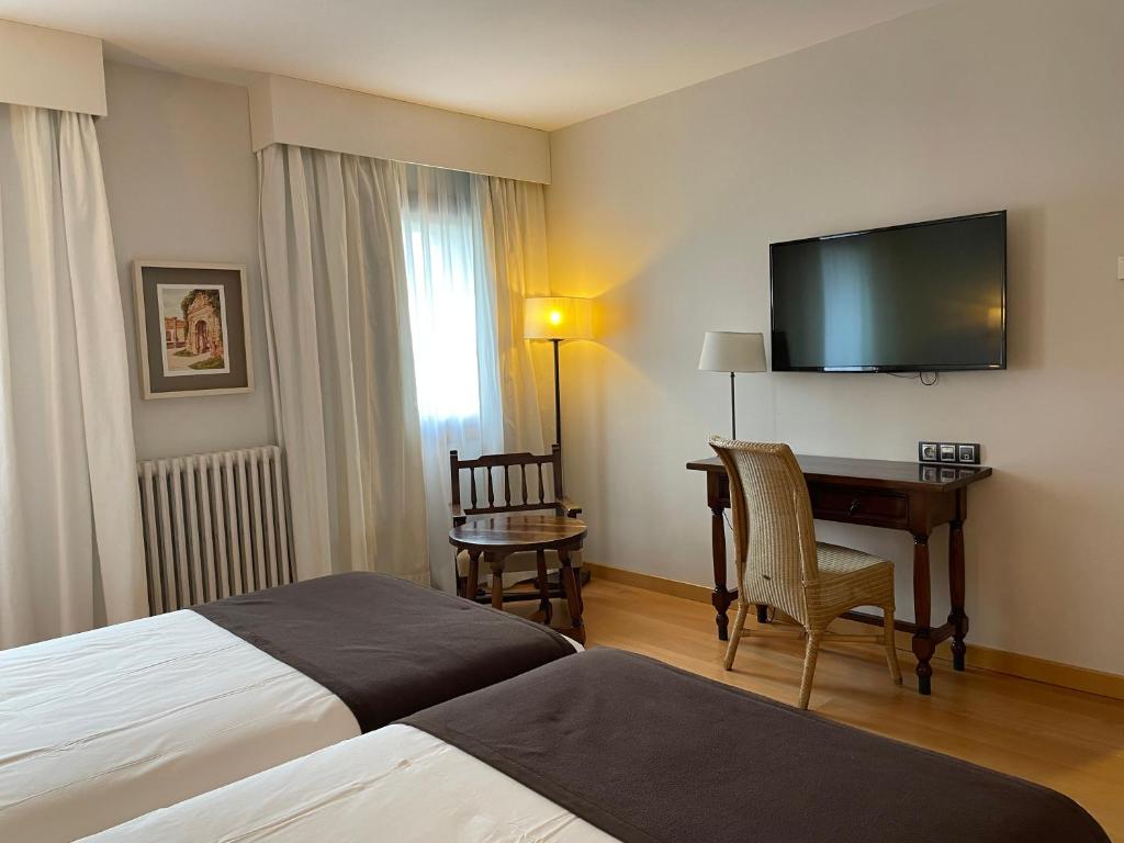 um quarto de hotel com uma cama, uma secretária e uma televisão em Parador de Puebla de Sanabria em Puebla de Sanabria
