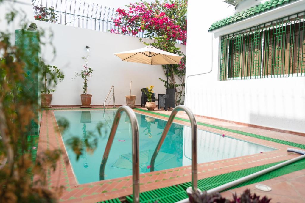 a swimming pool with an umbrella next to a building at VILLA MATI Maison D'hôtes in Tetouan