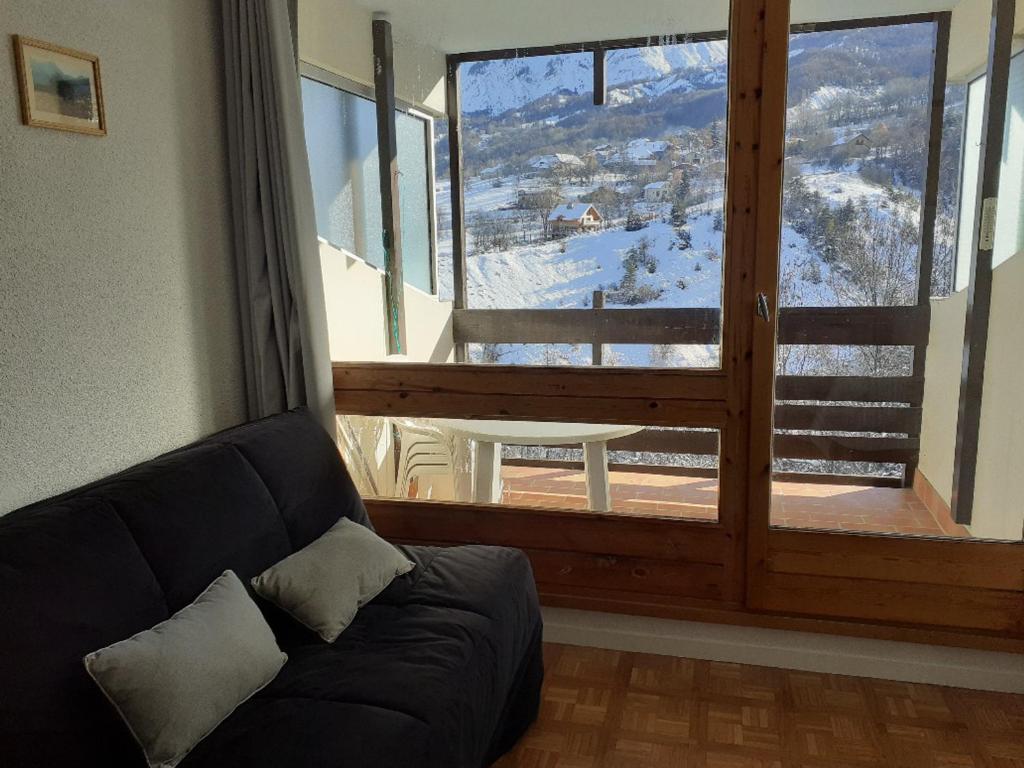 a living room with a couch in front of a large window at Studio Enchastrayes, 1 pièce, 4 personnes - FR-1-165A-114 in Enchastrayes