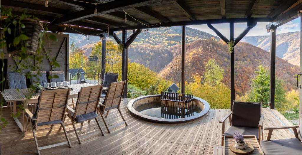 una terrazza con tavolo, sedie e vista sulle montagne di Amonte Mountain Resort a Muntele Rece