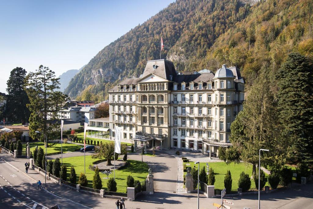 ein großes weißes Gebäude mit einem Berg im Hintergrund in der Unterkunft Grand Hotel Beau Rivage Interlaken in Interlaken