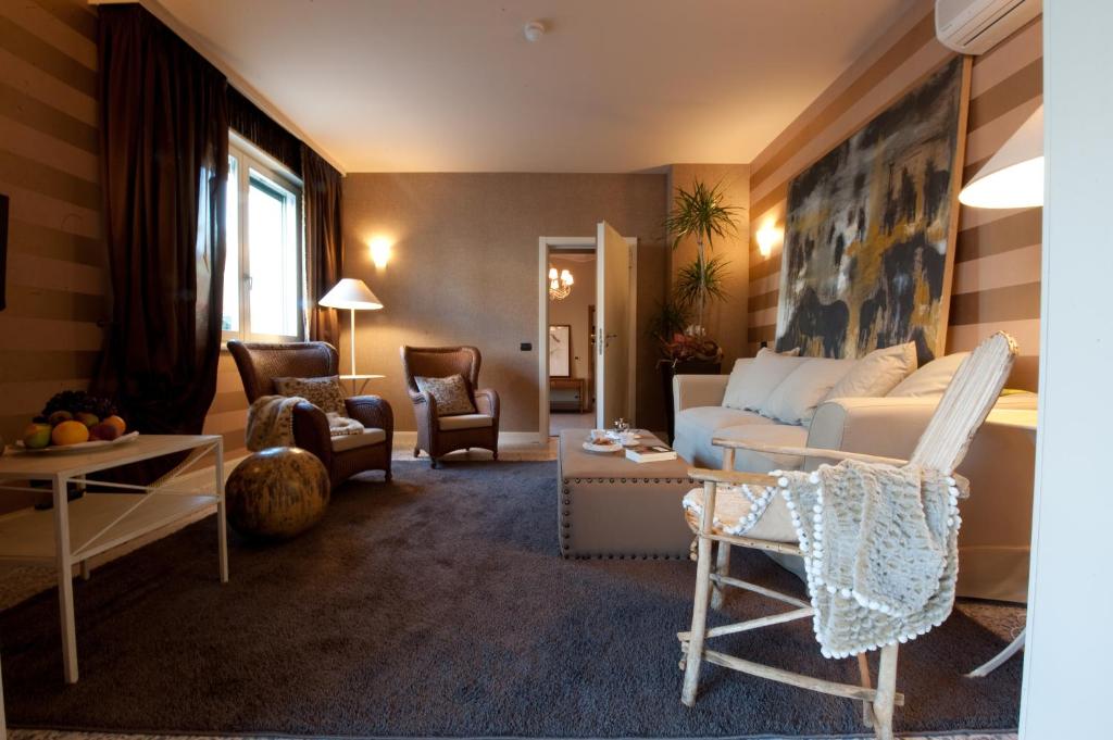 a living room with a white couch and chairs at Hotel Locanda Stendhal in Colorno