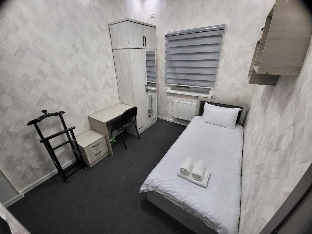 een kleine kamer met een bed, een bureau en een wastafel bij Shahriston GH in Tasjkent