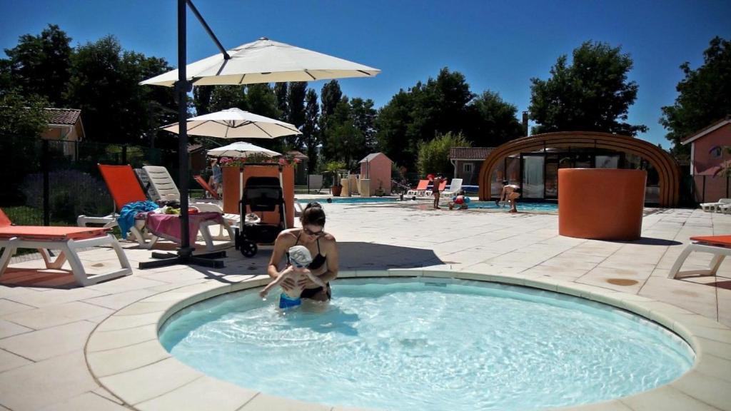 a man in a swimming pool with a child in the water at Le Hameau des Genets in Montlaur