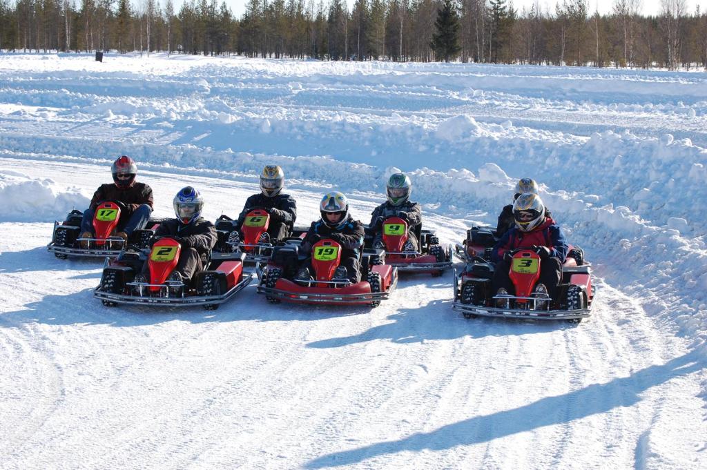 a group of people are riding on snowmobiles in the snow at Hotel Golden Circle Suites in Rovaniemi