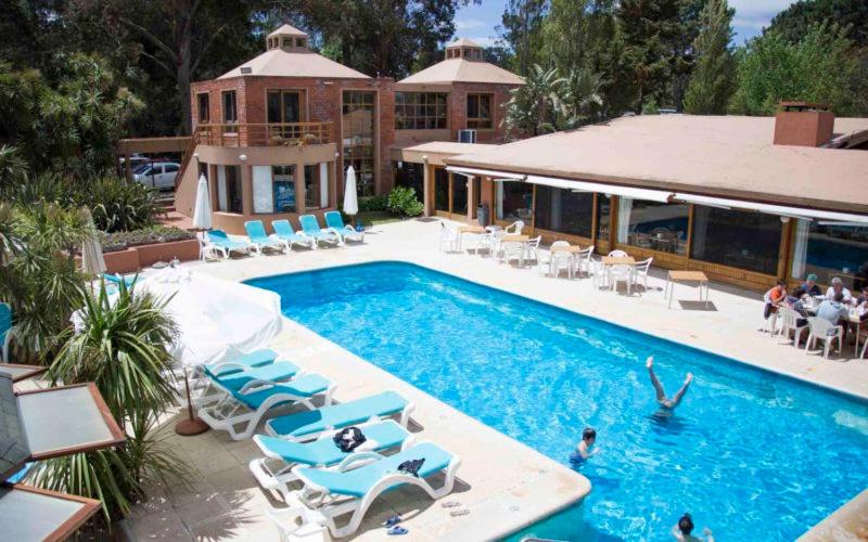 a swimming pool with blue chairs and a house at Rincon del Este in Punta del Este