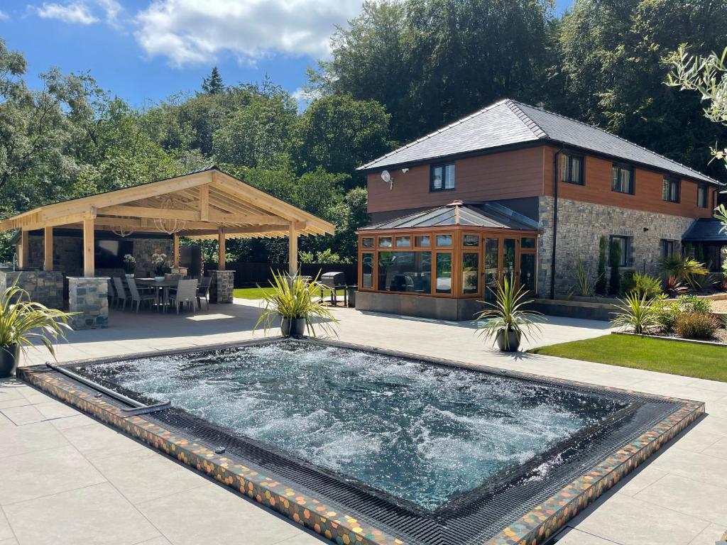 uma piscina em frente a uma casa com um edifício em Forest View em Coed Ely