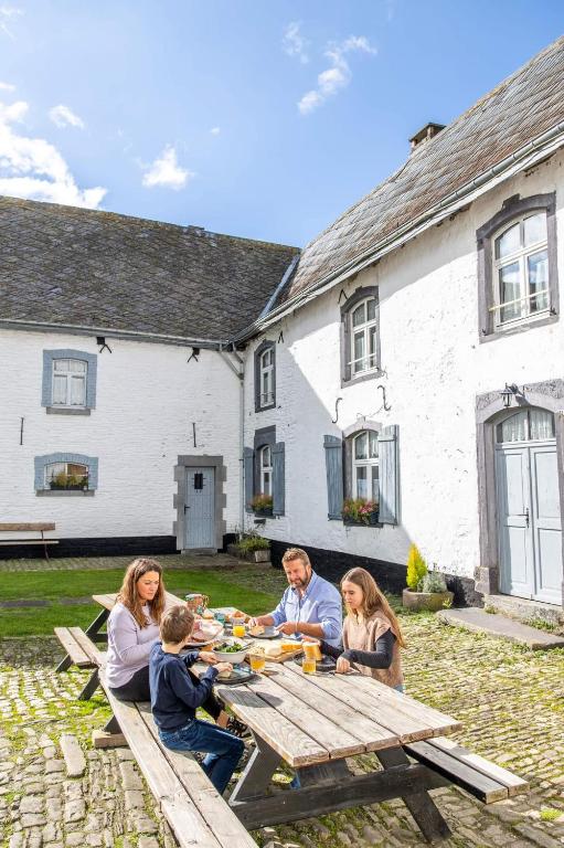 a group of people sitting around a picnic table at Manoir de Sterpigny, château-ferme 17ème siècle gîte la Tour in Gouvy