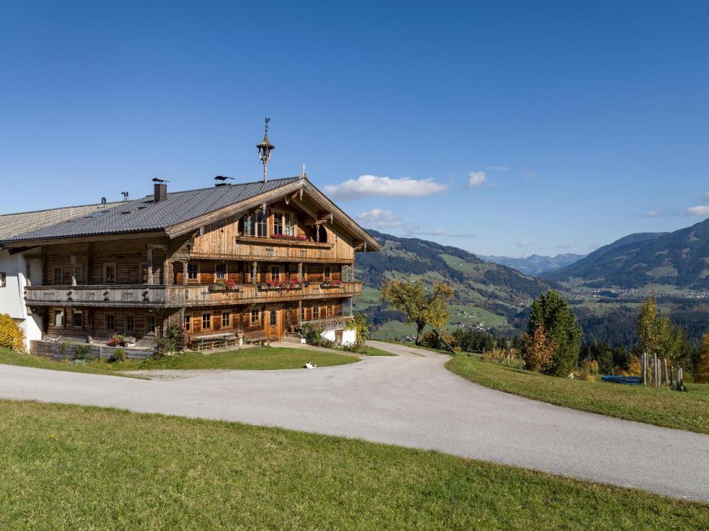 a large wooden house on a hill with a road at Ferienwohnung Schwalbennest in Hopfgarten im Brixental