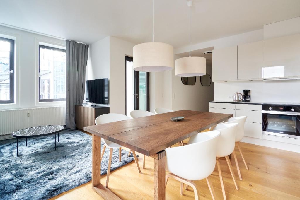 kuchnia i jadalnia z drewnianym stołem i białymi krzesłami w obiekcie Stylish 2BR w Private Balcony in CPH City Centre w Kopenhadze