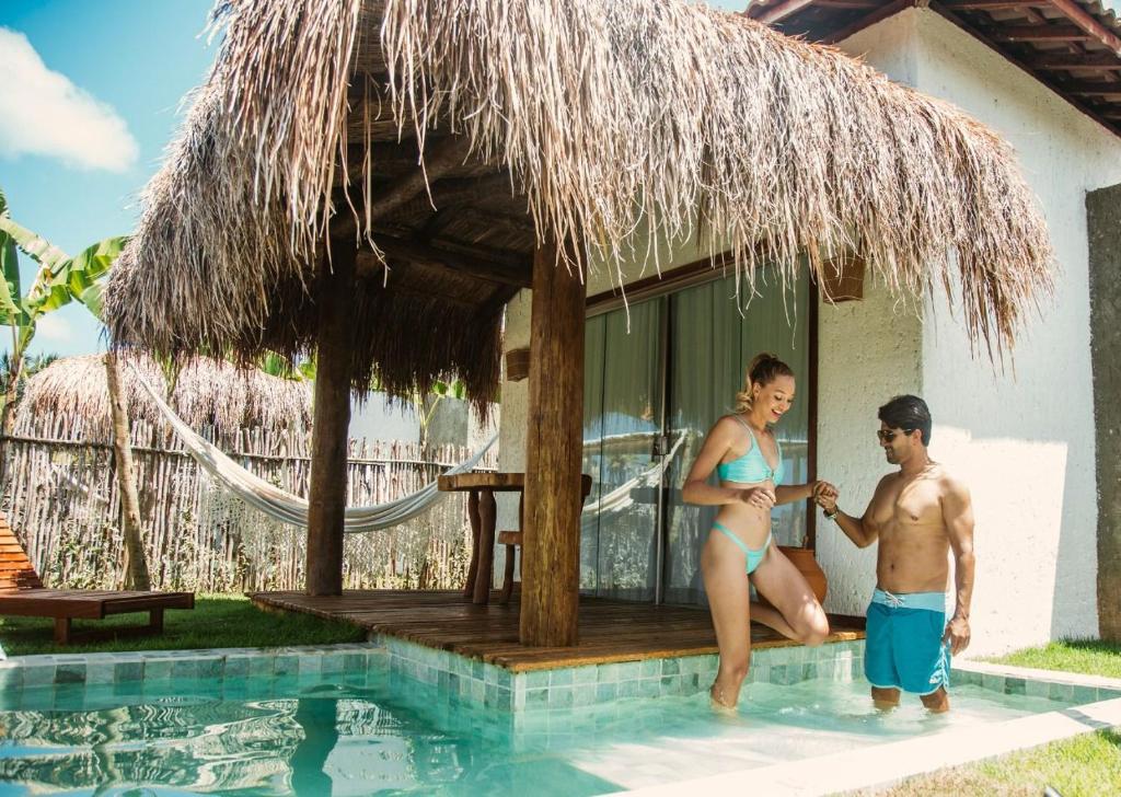 a man and a woman sitting in a swimming pool at POUSADA ZAYA in São Miguel dos Milagres