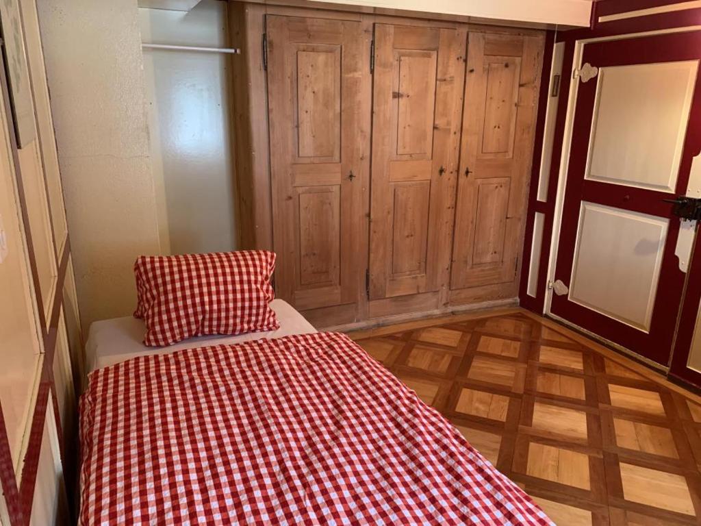 um quarto com uma cama com um cobertor xadrez vermelho e branco em Revier Hazzo's Biasca em Hätzingen