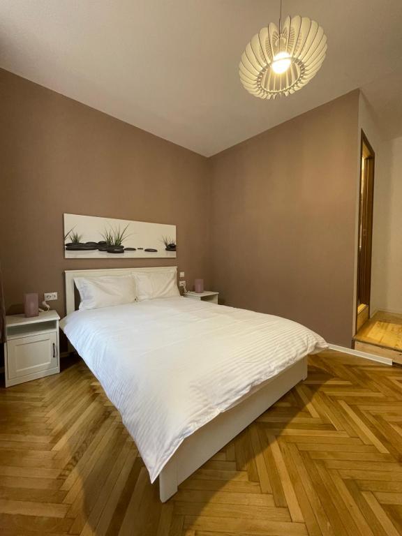 - une chambre avec un grand lit blanc et un lustre dans l'établissement Schei Central Studios in the heart of Brasov, à Braşov