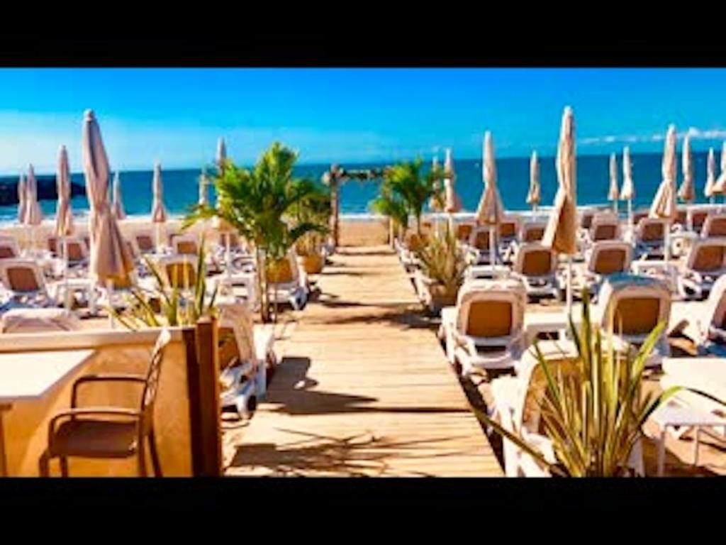 a beach with chairs and tables and umbrellas at Bungalow de 3 chambres avec piscine partagee et terrasse a Vias a 1 km de la plage in Vias