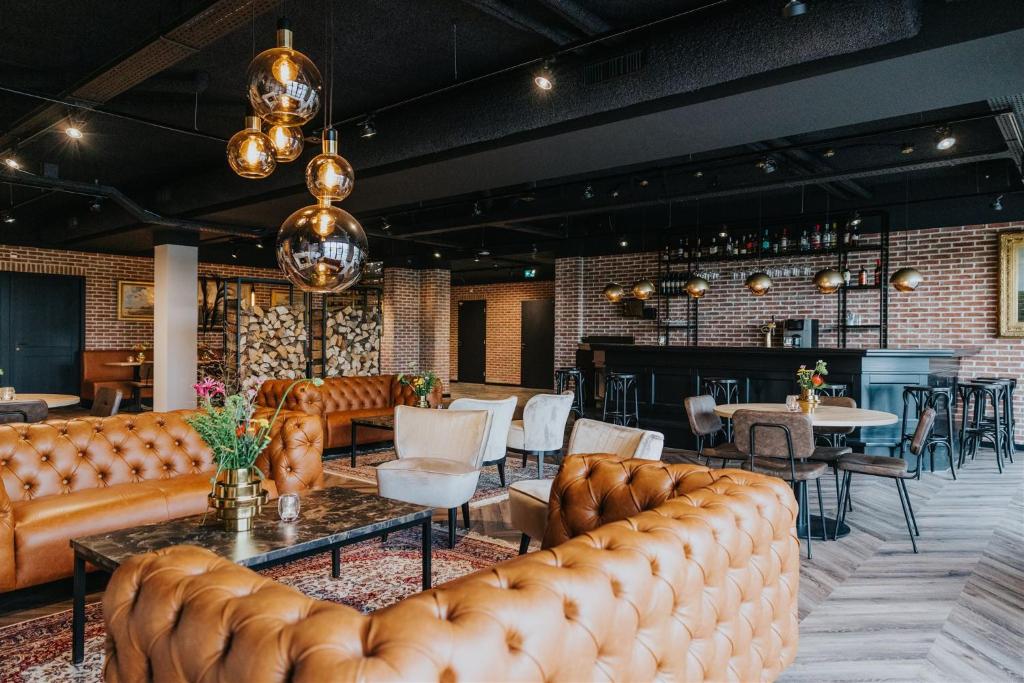 a lobby with leather couches and tables and a bar at Hotel Sportsbar & Brasserie Dorhout Mees in Biddinghuizen