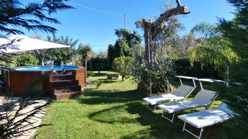 2 chaises blanches assises dans l'herbe à côté d'une piscine dans l'établissement Villa Piana - Con Piscina e Giardino privato nel Salento, à Tricase