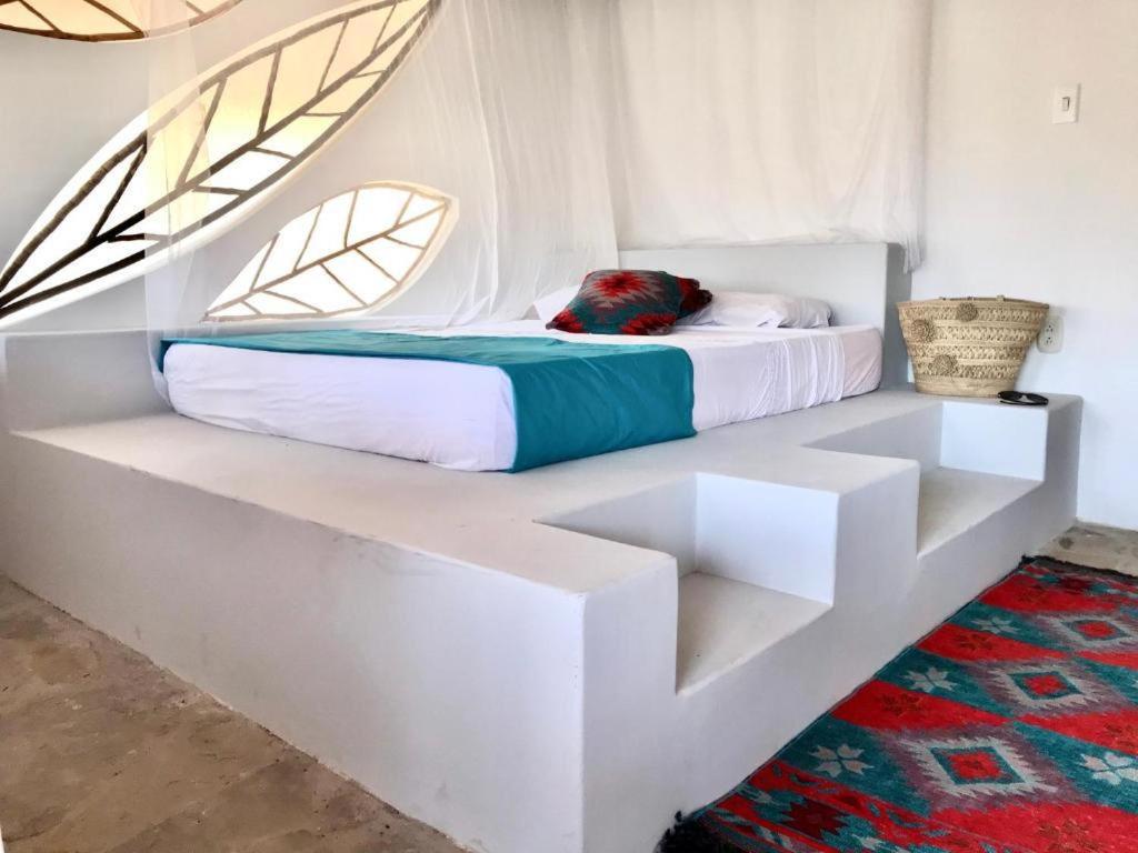 a white bed in a white room with a table at Kamajorú Ecohabitat in Tubará