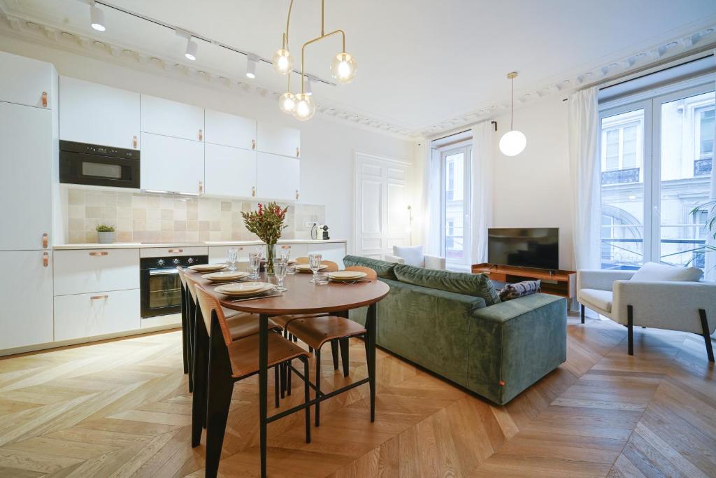 a kitchen and living room with a table and a couch at Parisuites Central Grands boulevards Design Folies Bergères in Paris